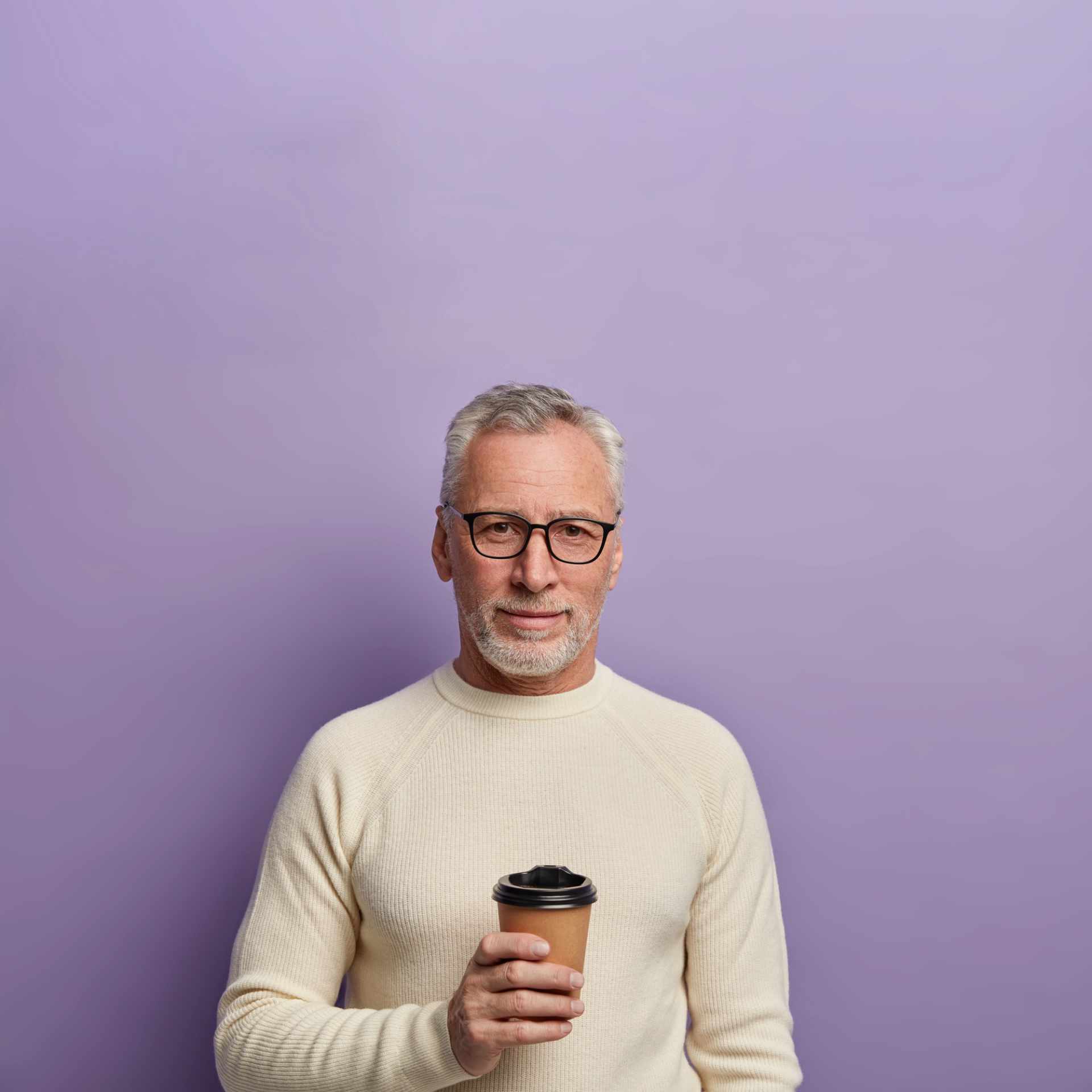grey-haired-senior-man-wears-transparent-glasses-white-sweater-stands-cools-hot-beverage-enjoys-pleasant-conversation-poses-against-purple-background